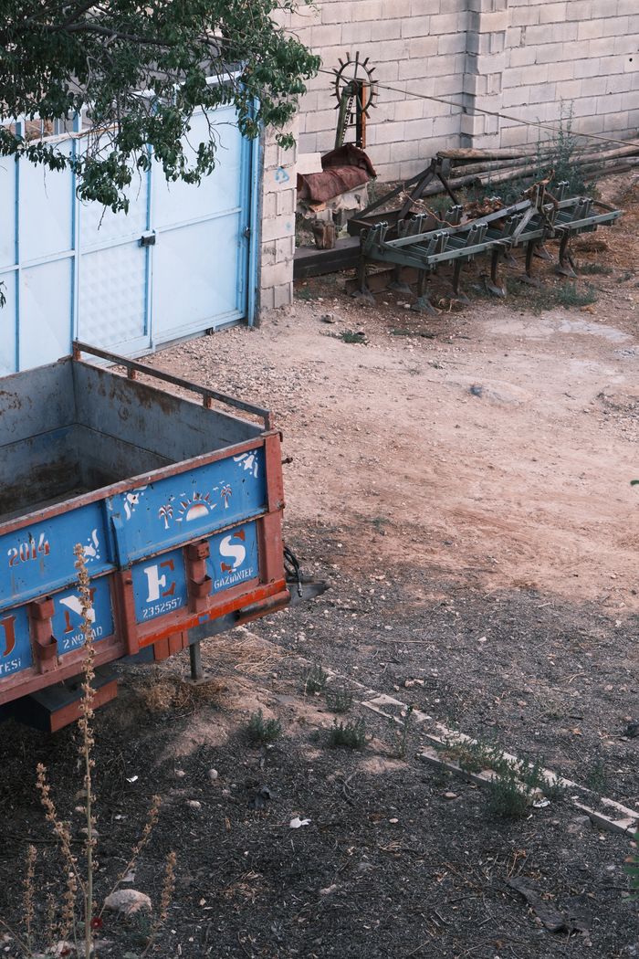 A deserted lot with a blue industrial trailer and scattered machinery parts, showcasing urban decay.